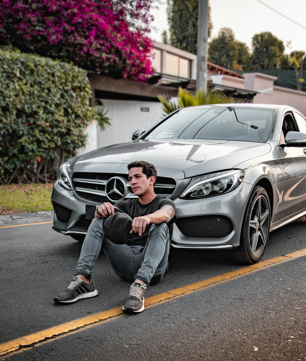 unknown celebrity sitting siting beside silver Mercedes-Benz car outdoors thinking about The Importance of Keeping Your Commercial Auto Coverage Up-to-Date